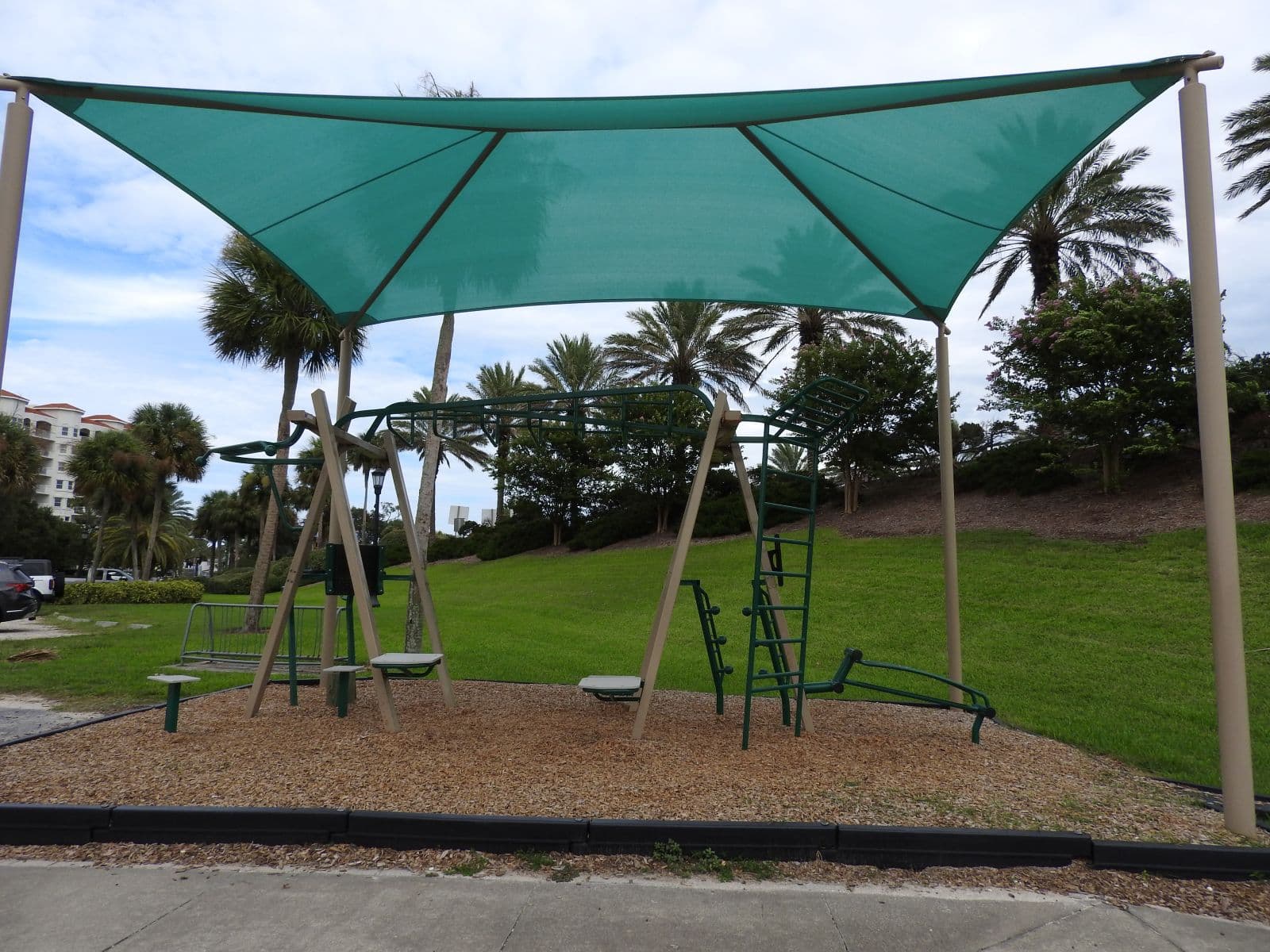Shaded outdoor exercise equipment on the landscaped grounds at Fortunato Park.