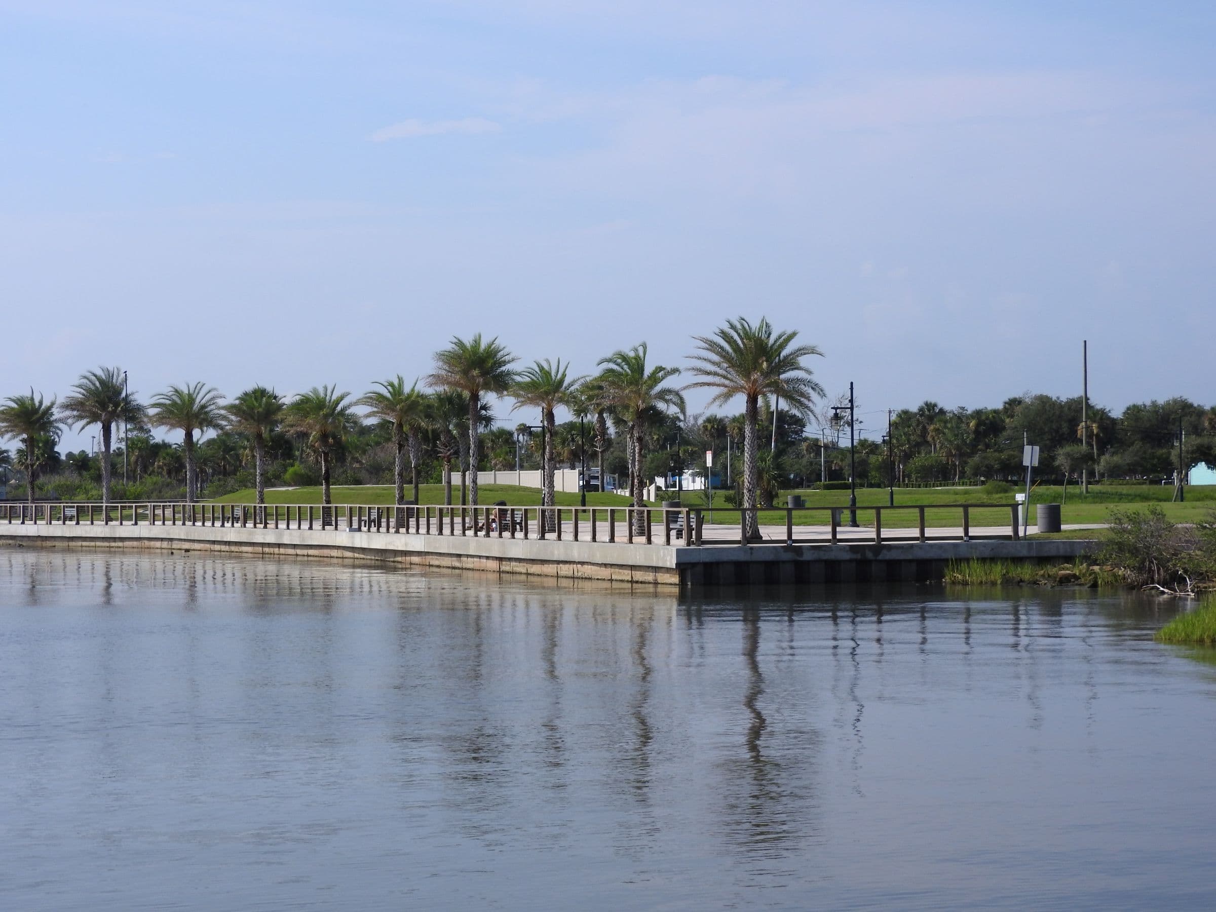 Palm-lined Riverwalk Park waterfront reflected in the Halifax River.