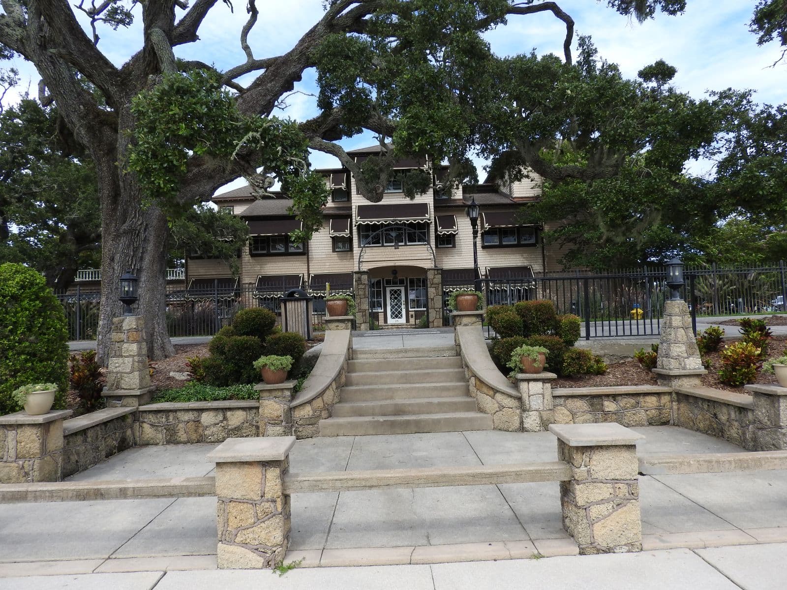 The Casements framed by mature live-oak branches and formal stone steps.